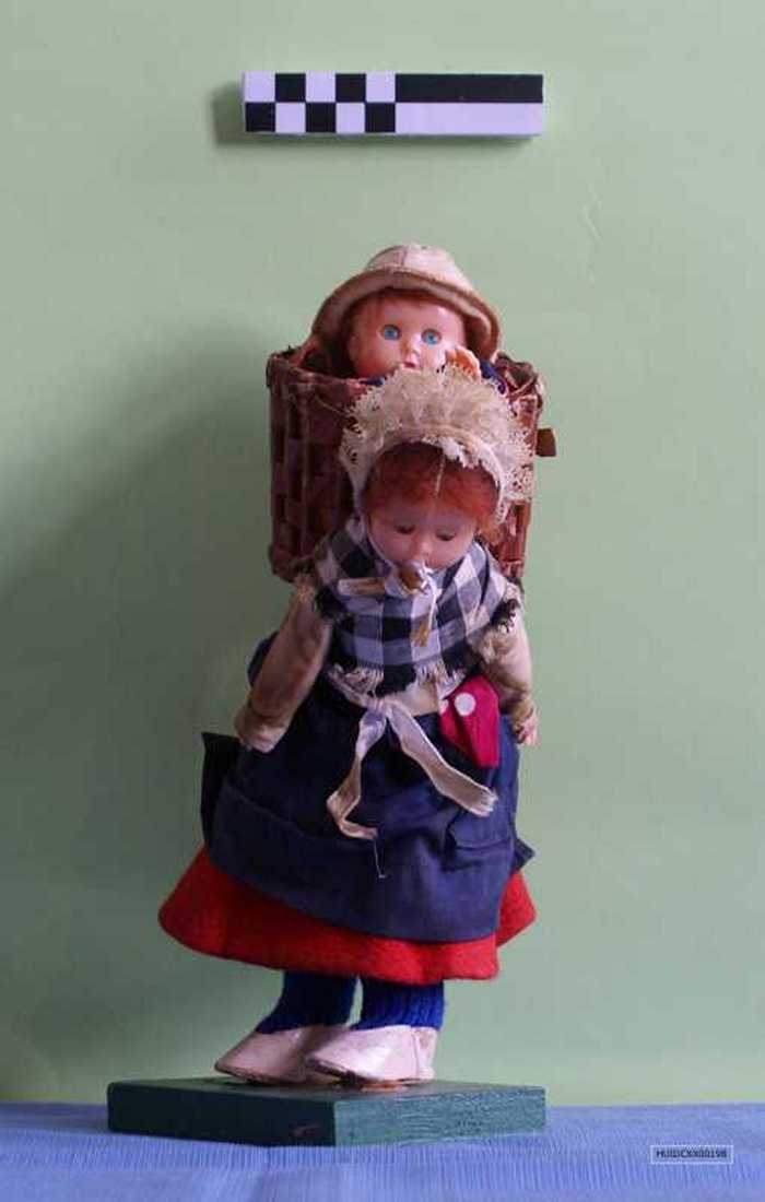 Popje: vissersvrouw met mand op de rug waarin een kind zit